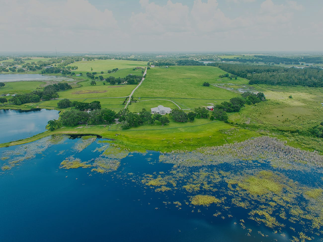 Aerial view of Covington Farm with lakeside shoreline, open pastures, and scenic event spaces in Dade City, Florida.